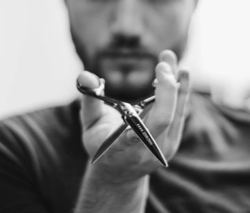 shallow focus photo of man holding scissors